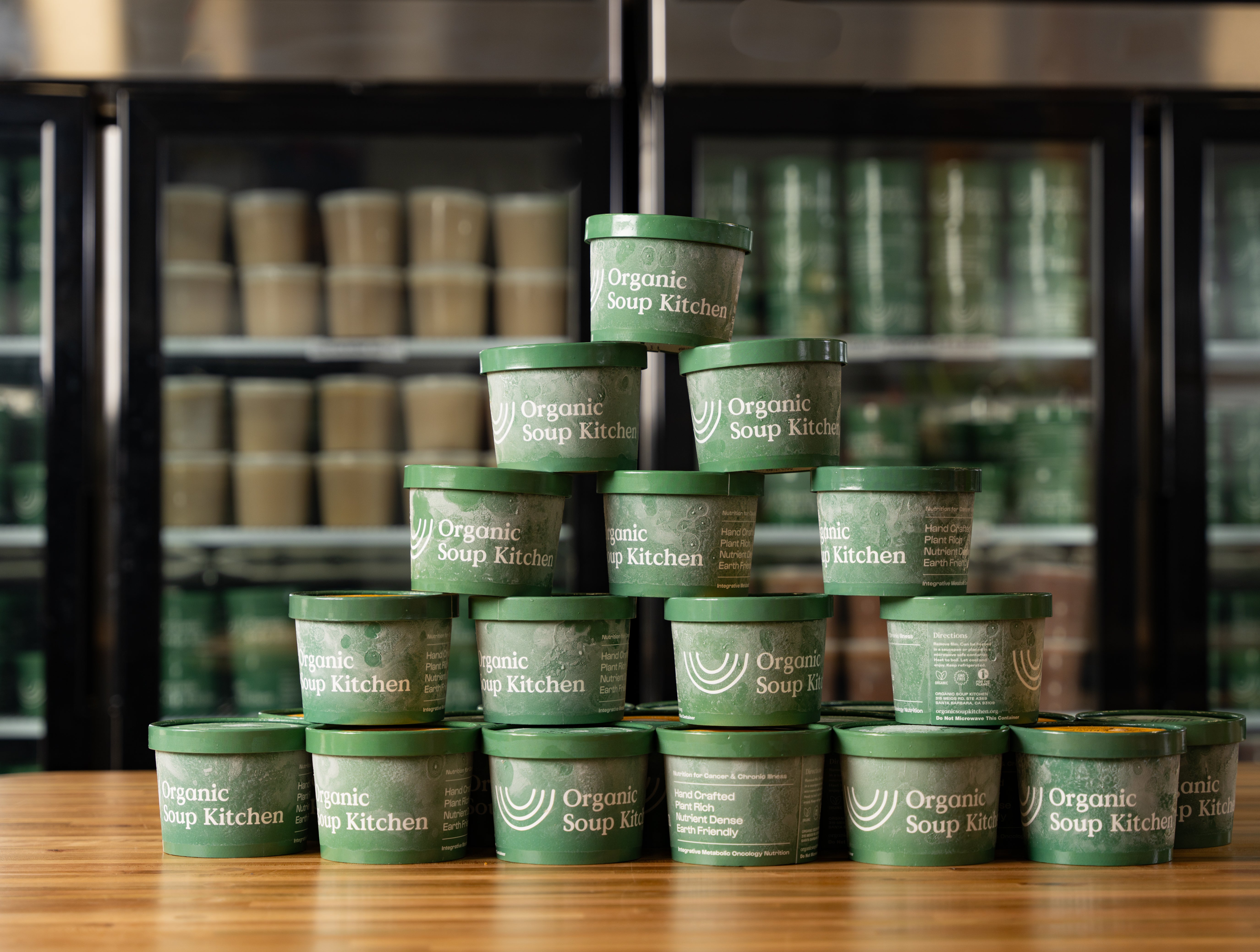 Organic Soup Kitchen soup containers stacked in front of refrigerators
